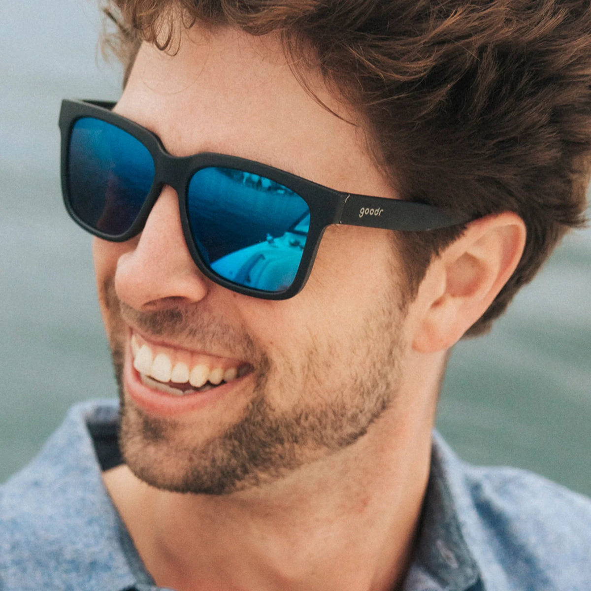 Fit and style showcase of black sunglasses with blue reflective lenses. Water repellent and capable of floating.