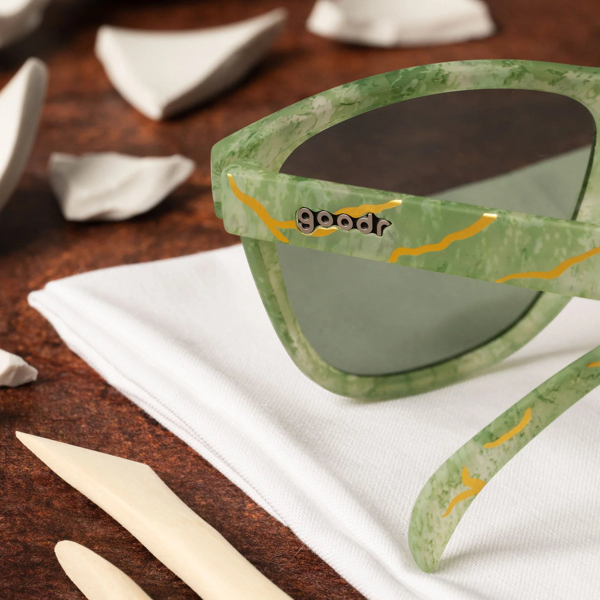 Marbled green square shaped sunglasses with a prominent golden line pattern, reminiscent of Kintsugi. 